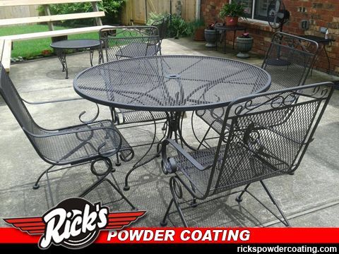 Black powder-coated wrought-iron patio table and chairs on a concrete patio.