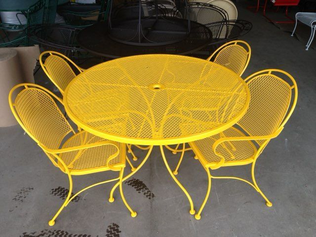 Yellow metal patio table with four matching chairs on a concrete floor