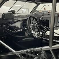 Race car interior with steering wheel, roll cage, and dashboard visible