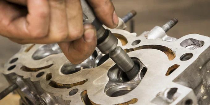 Mechanic using a valve lapping tool on an engine cylinder head close-up