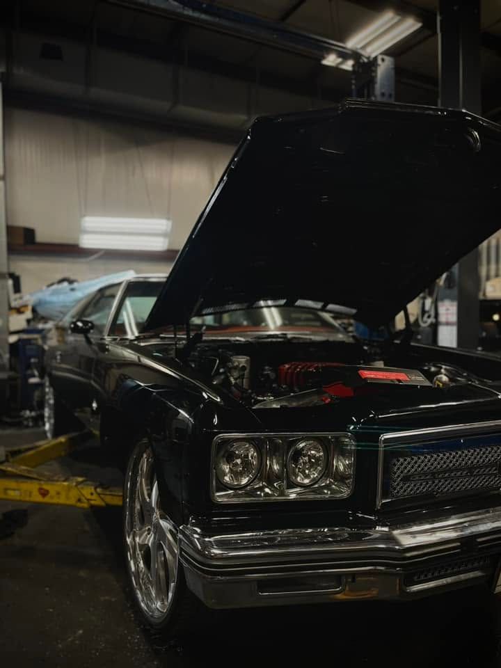 Classic black car in a garage with its hood open, showing the engine.