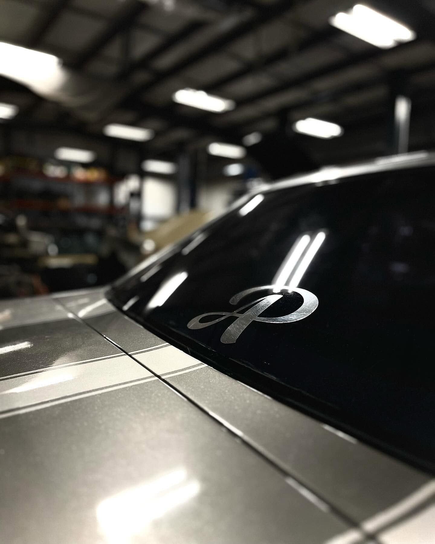 Close-up of a silver car windshield with a ribbon decal in a dim garage