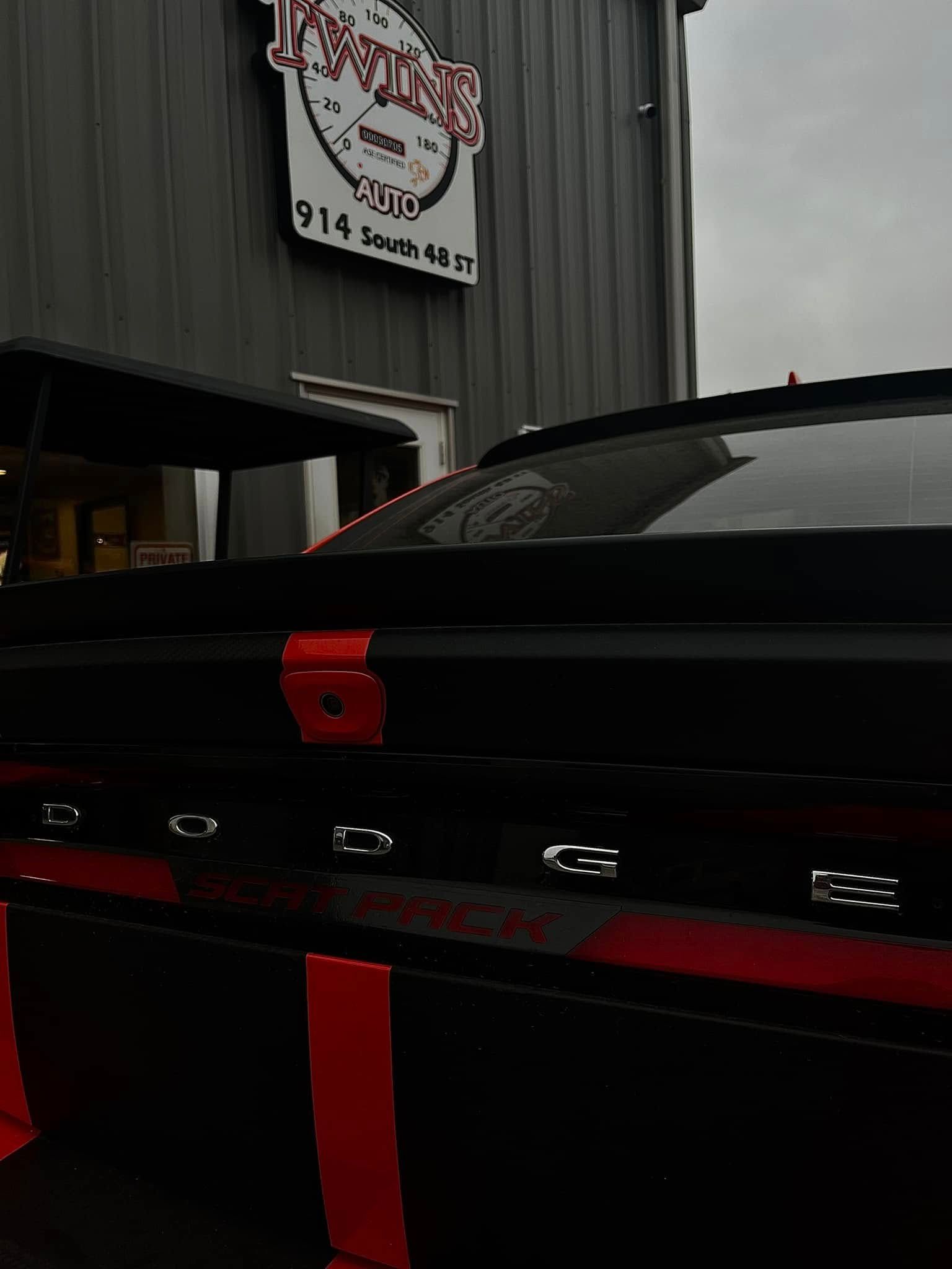 Black sports car with red accents parked inside a garage-like workshop