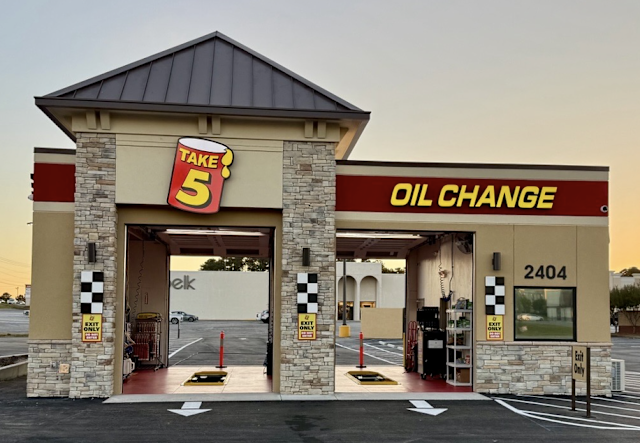 Take 5 Oil Change storefront with stone pillars, red-and-yellow sign, and empty drive-through bays