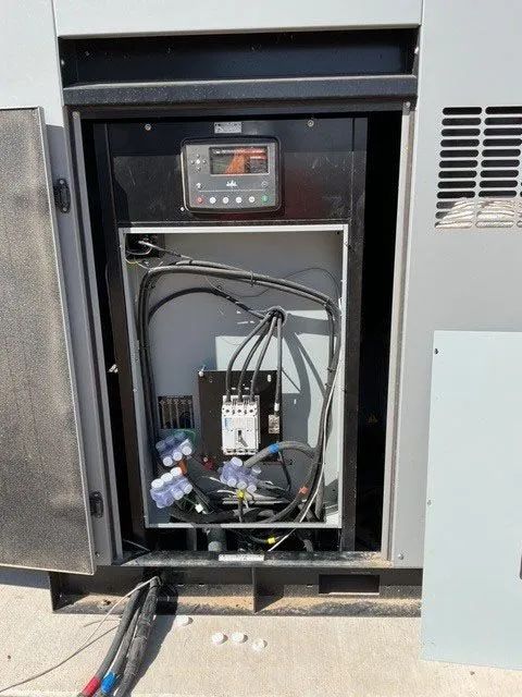 Open electrical cabinet with wiring, control panel, and components inside a gray metal enclosure.