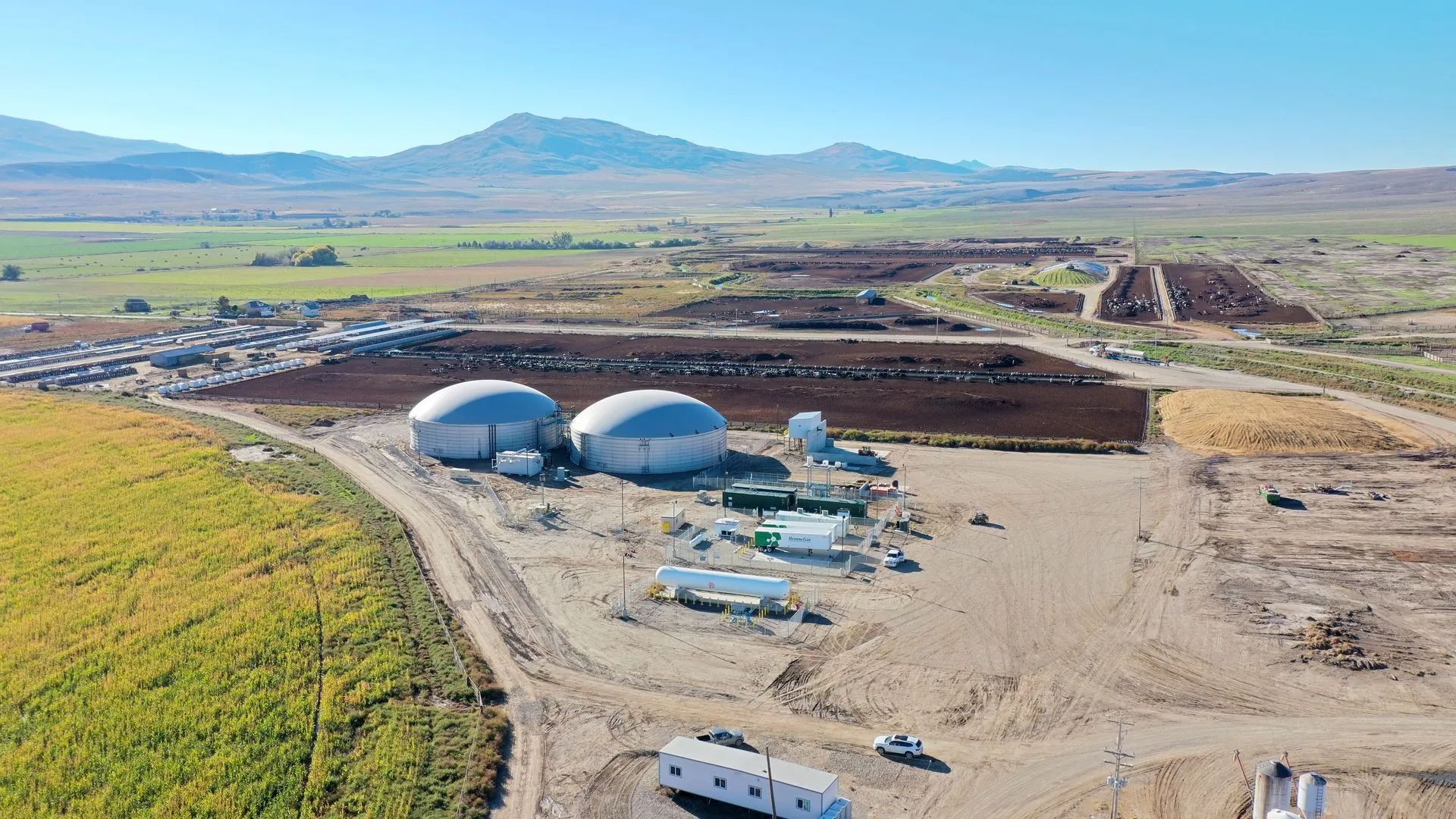 Construction site with two large white domes in a barren landscape, mountains in the distance.