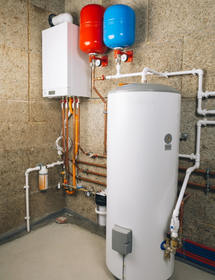 Boiler room with white tank, wall unit, red and blue expansion tanks, and exposed pipes on concrete floor