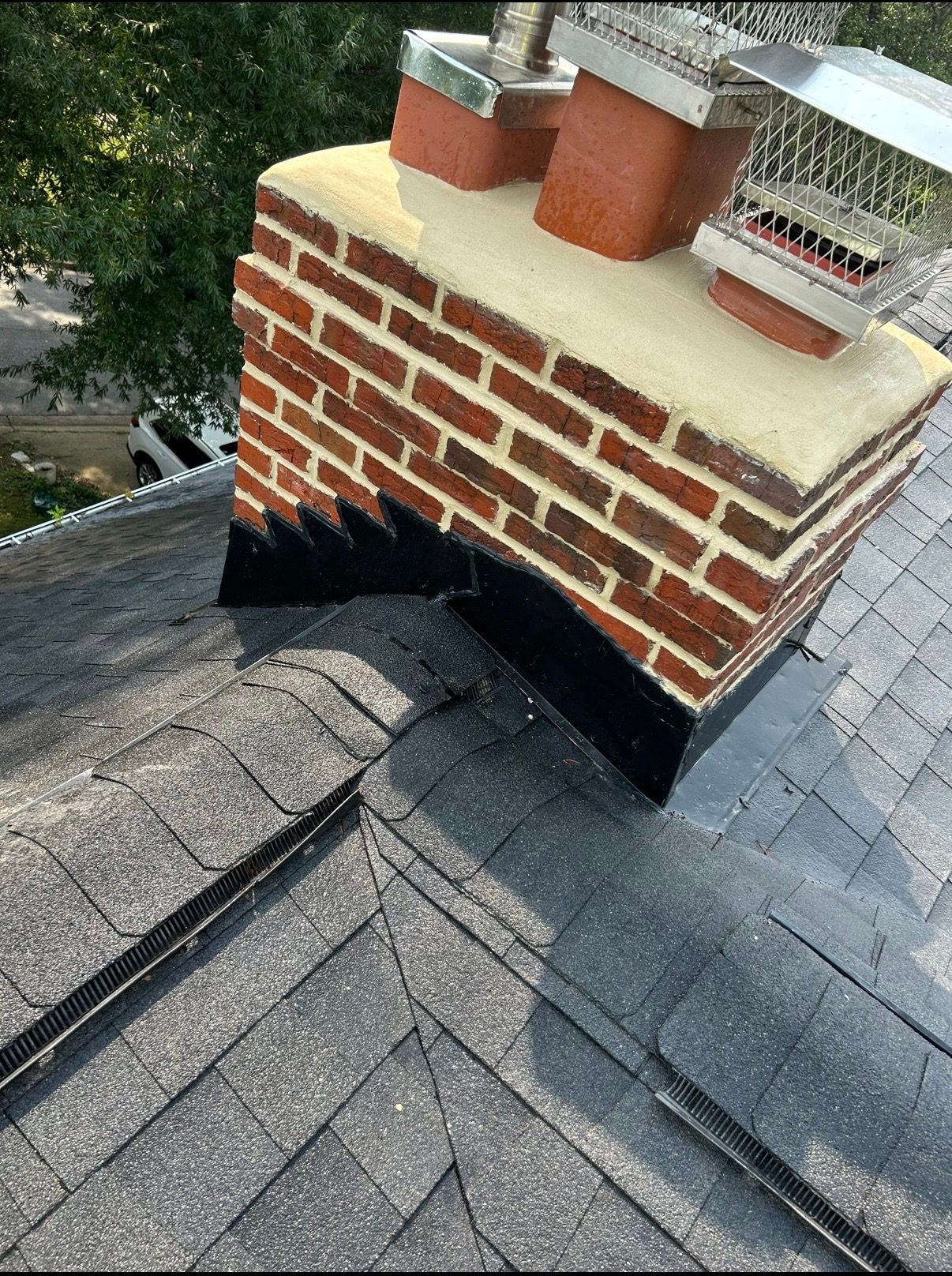 Brick chimney with two terra-cotta pots on a dark shingled roof, viewed from above