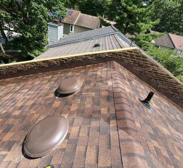 Roof shingles with two round vents and a chimney pipe on a residential house