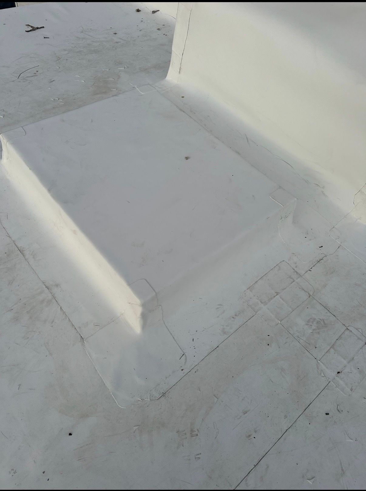Concrete rooftop with a raised rectangular platform and white wall corner