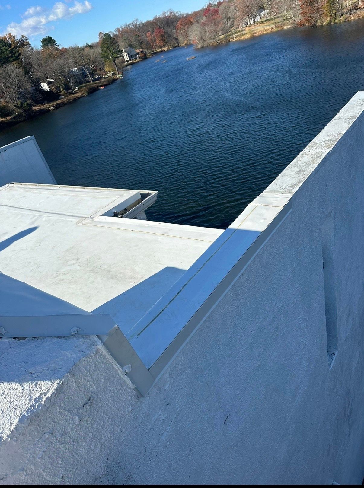 Concrete bridge over a blue lake with wooded shoreline and clear sky