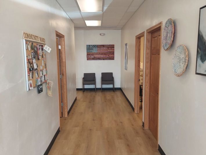 A hallway with wooden floors and a bulletin board on the wall