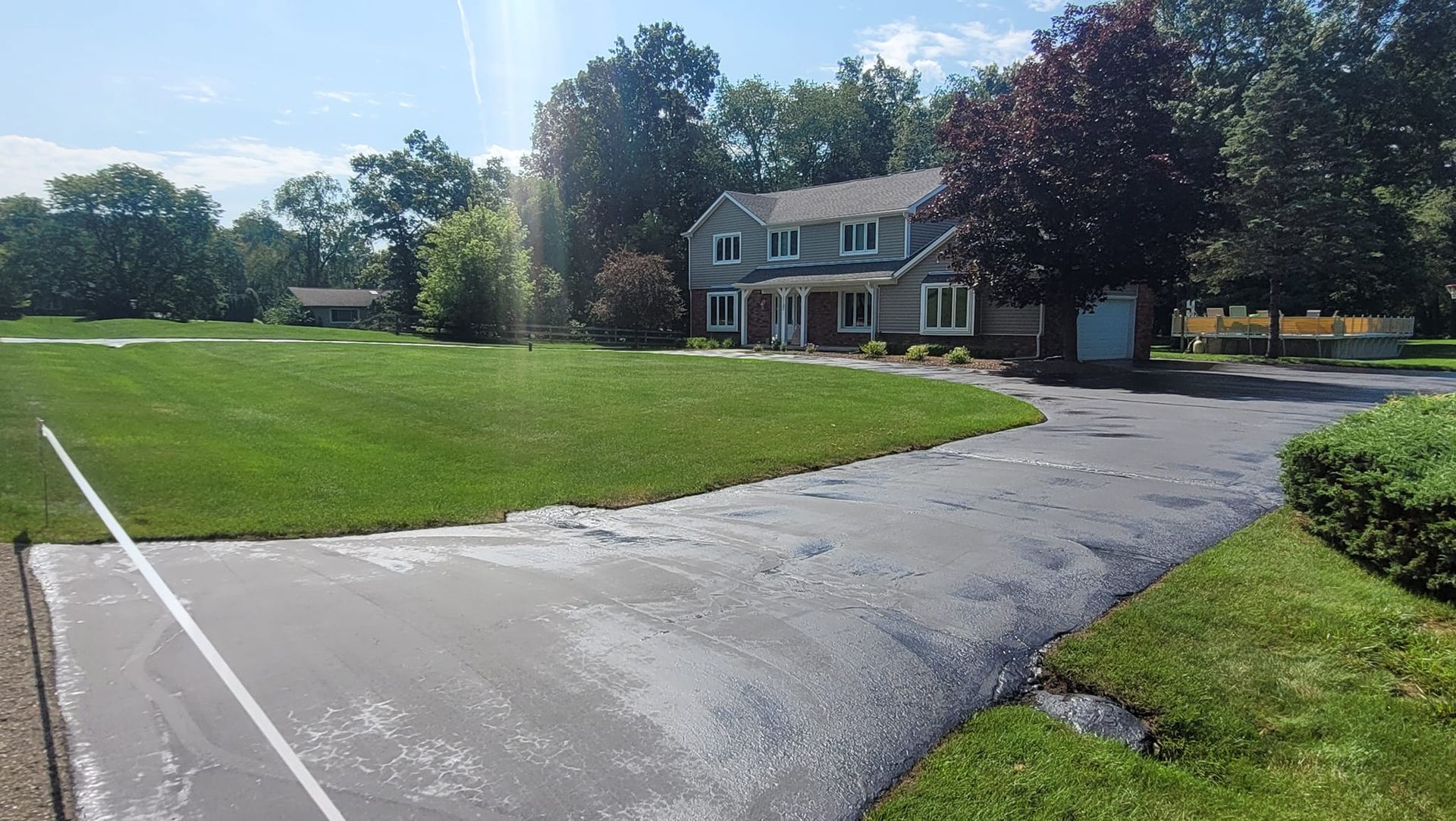 A two-story gray house with a red door and green lawn. A driveway leads up to the house.
