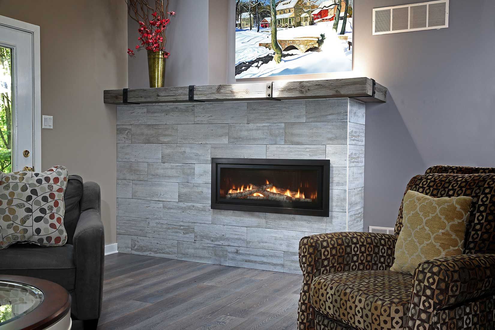 Fireplace with gray stone facing, wood mantel, and a lit electric fire. Seating area with sofas.