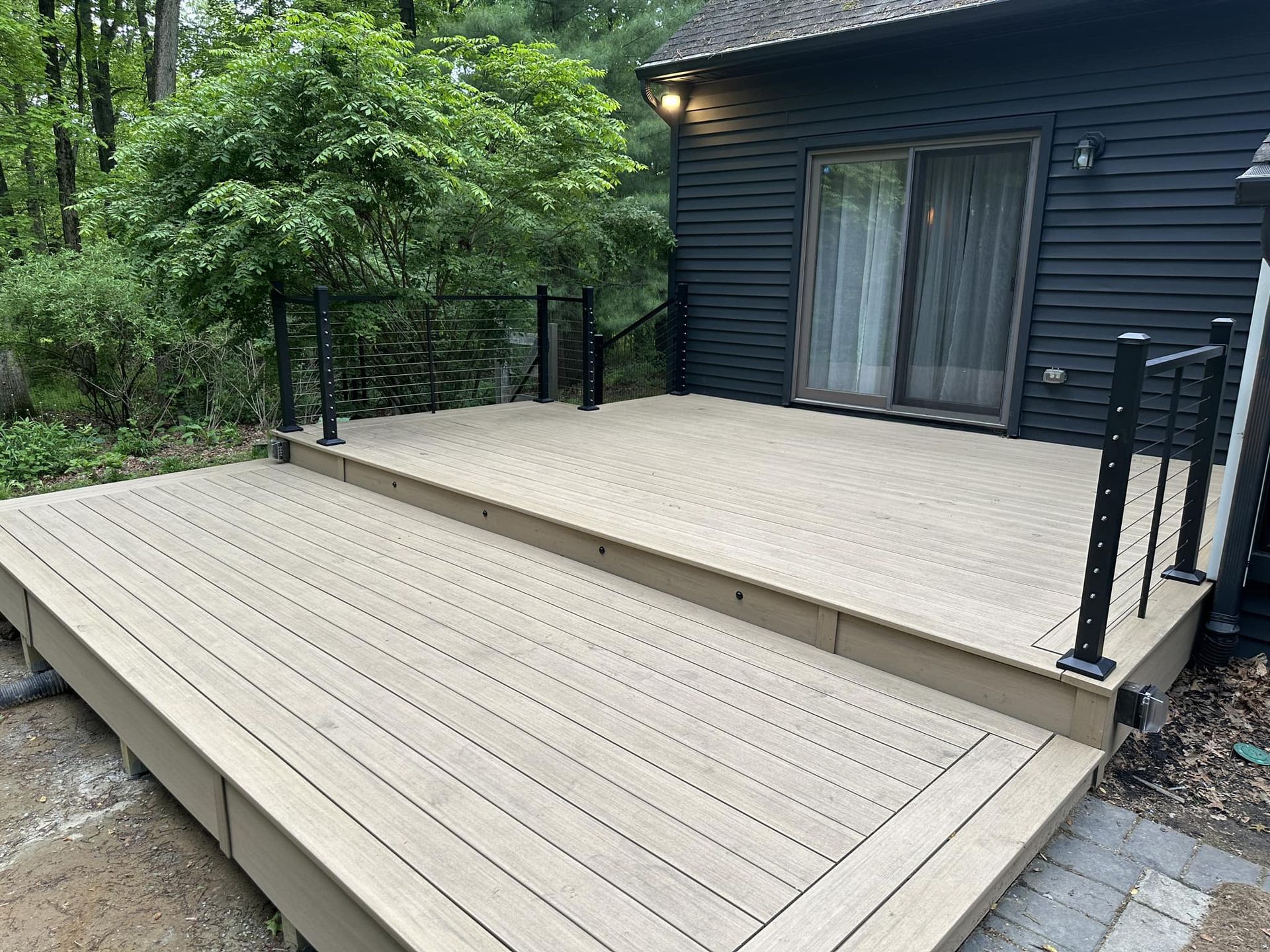 A wooden deck is sitting in front of a black house.