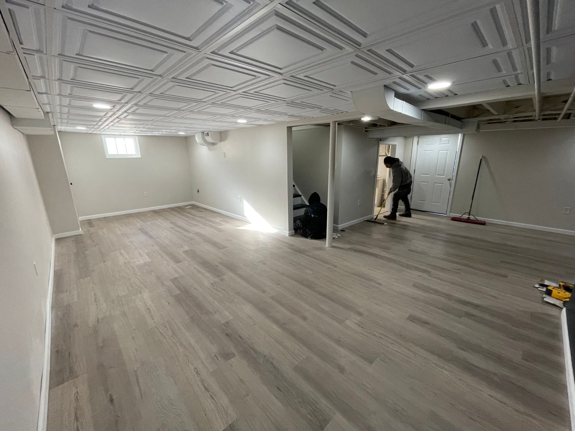 A man is sweeping the floor of a basement with a broom.