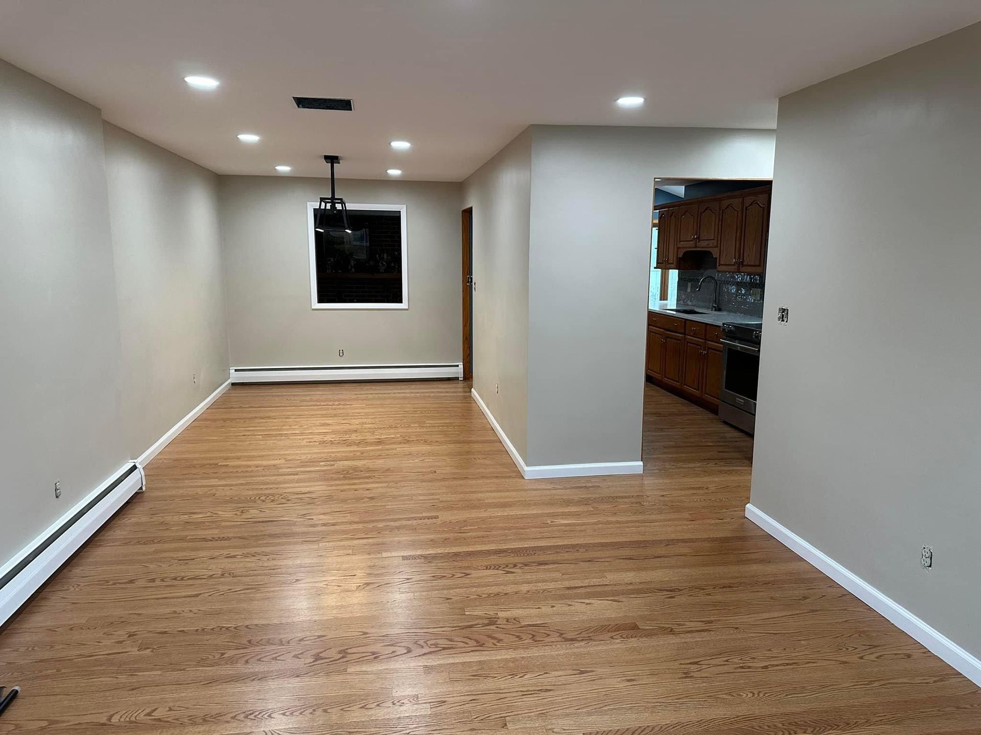An empty room with hardwood floors and white walls
