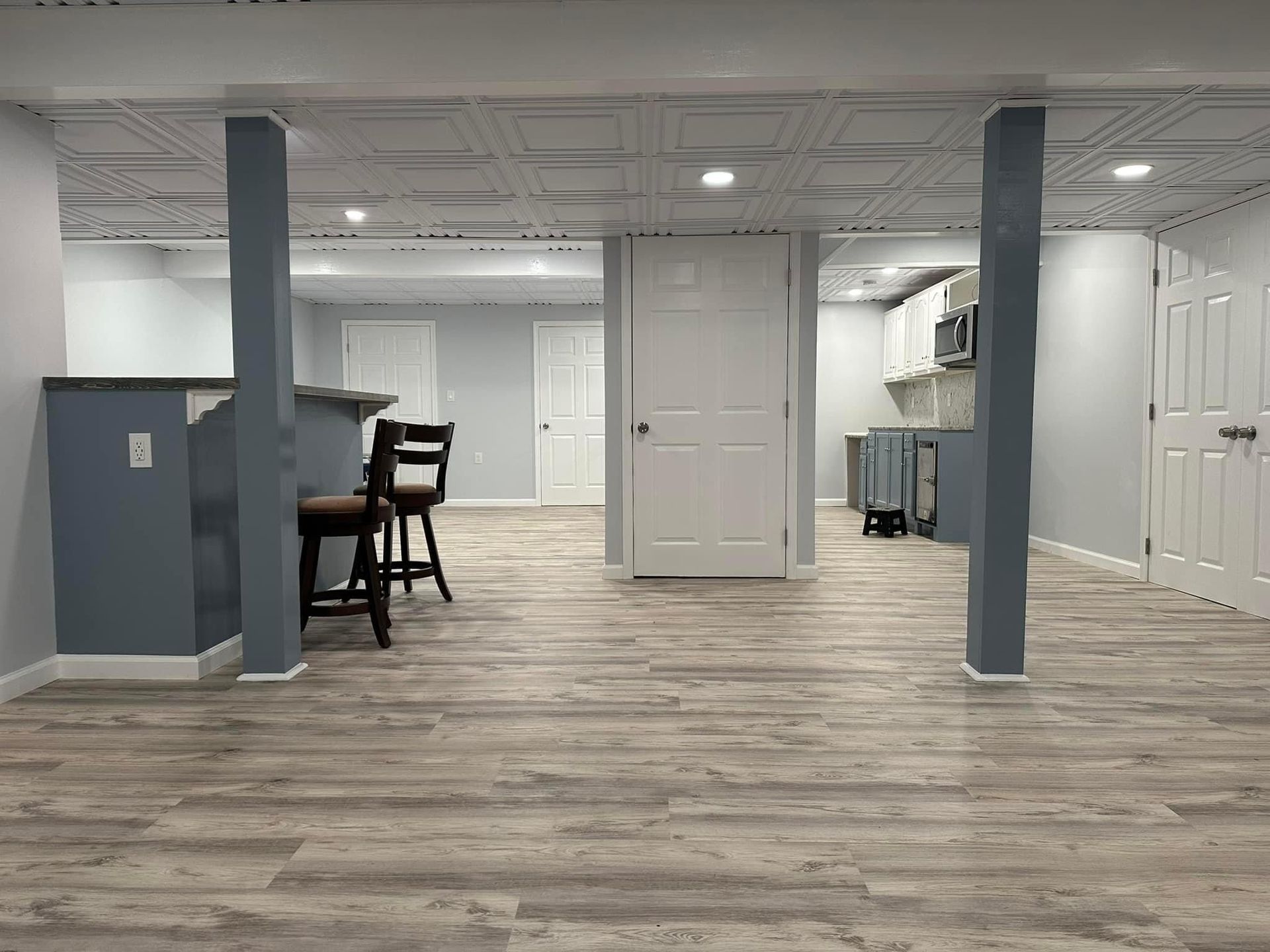 A basement with hardwood floors , a bar , and a kitchen.