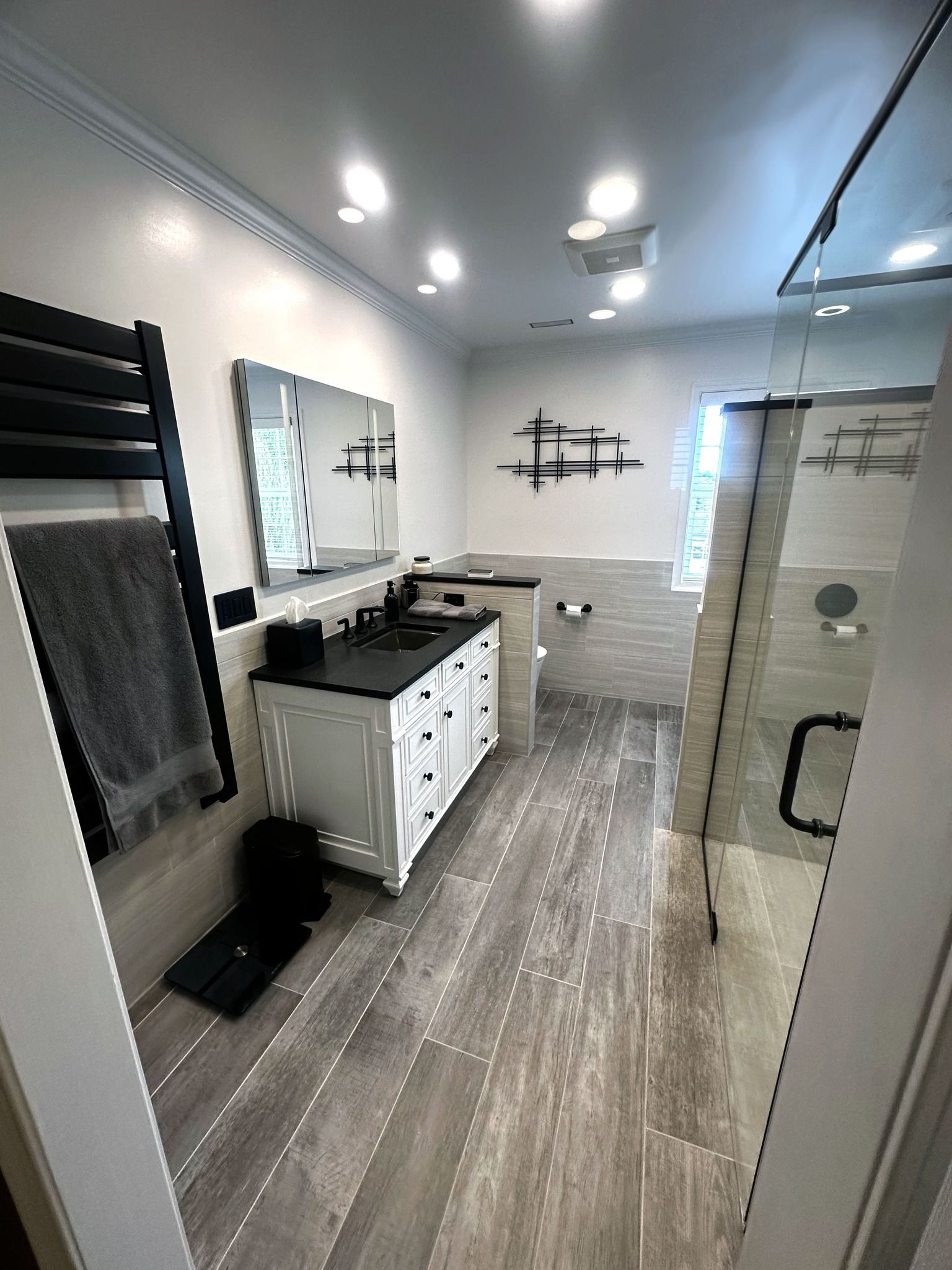 A bathroom with a walk in shower , sink , mirror and towel rack.