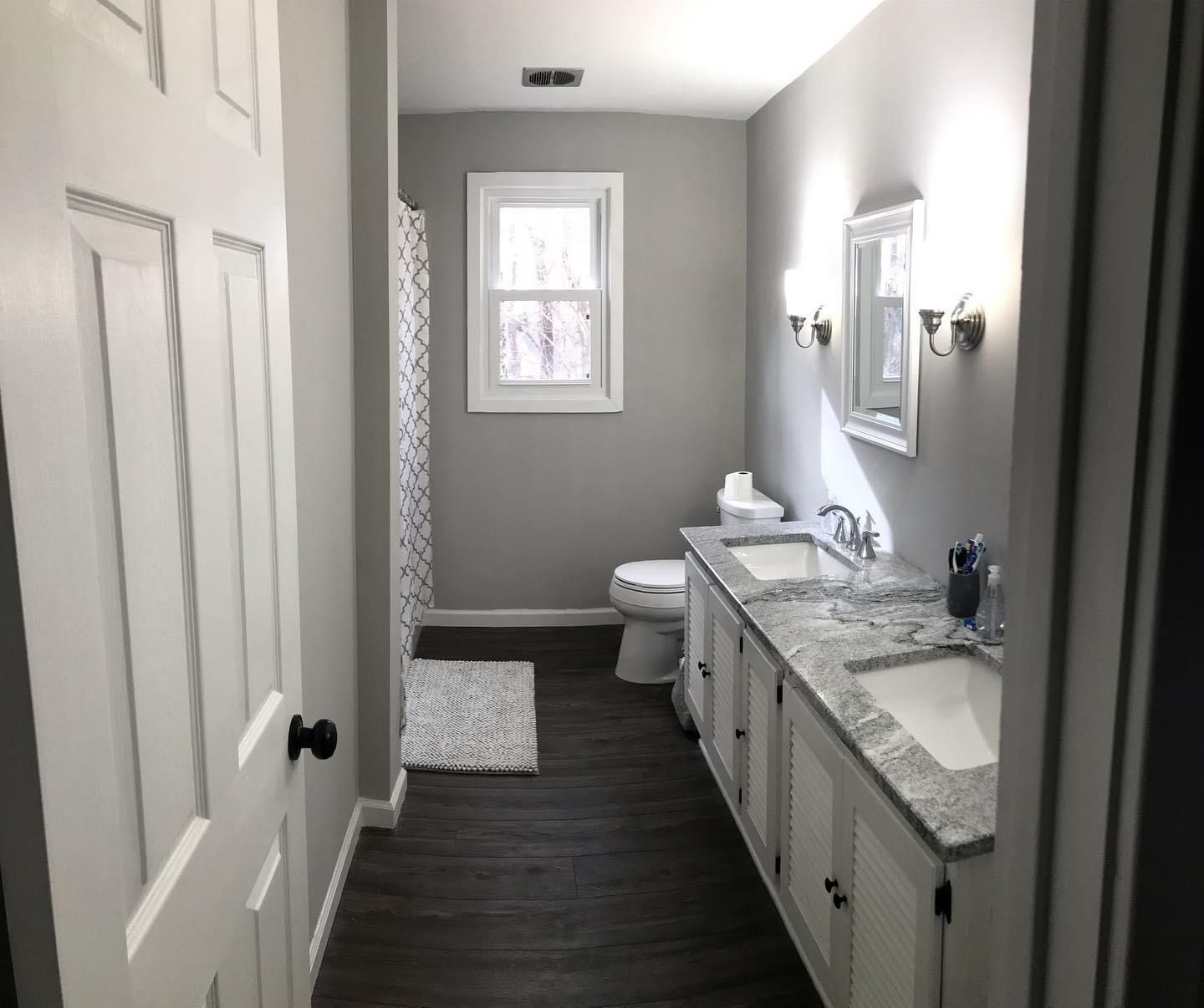 A bathroom with two sinks , a toilet and a window