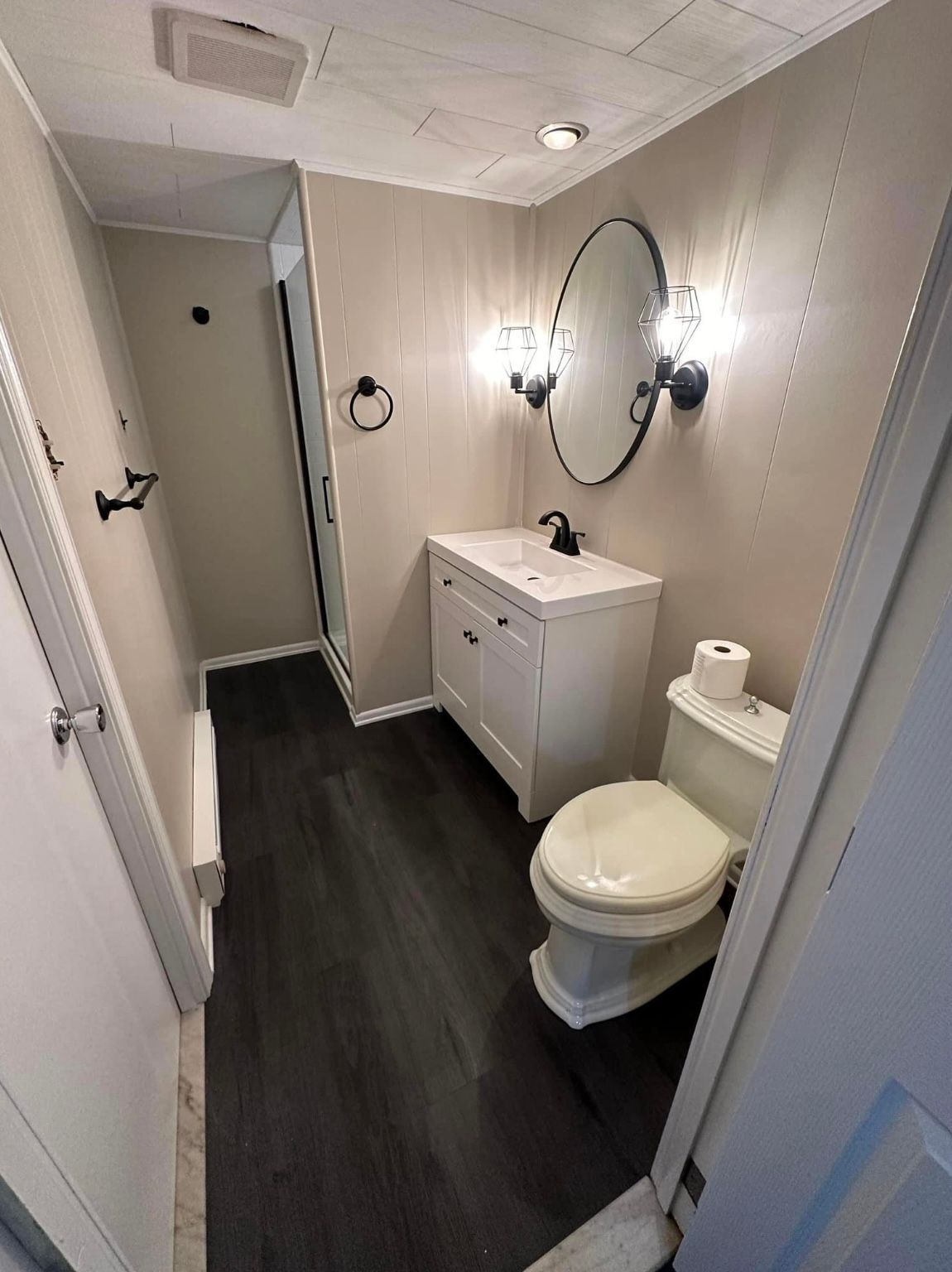 A bathroom with a toilet , sink and mirror.