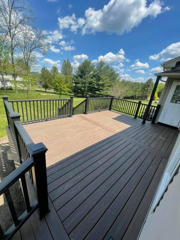 A large wooden deck with a black railing and stairs leading up to it.