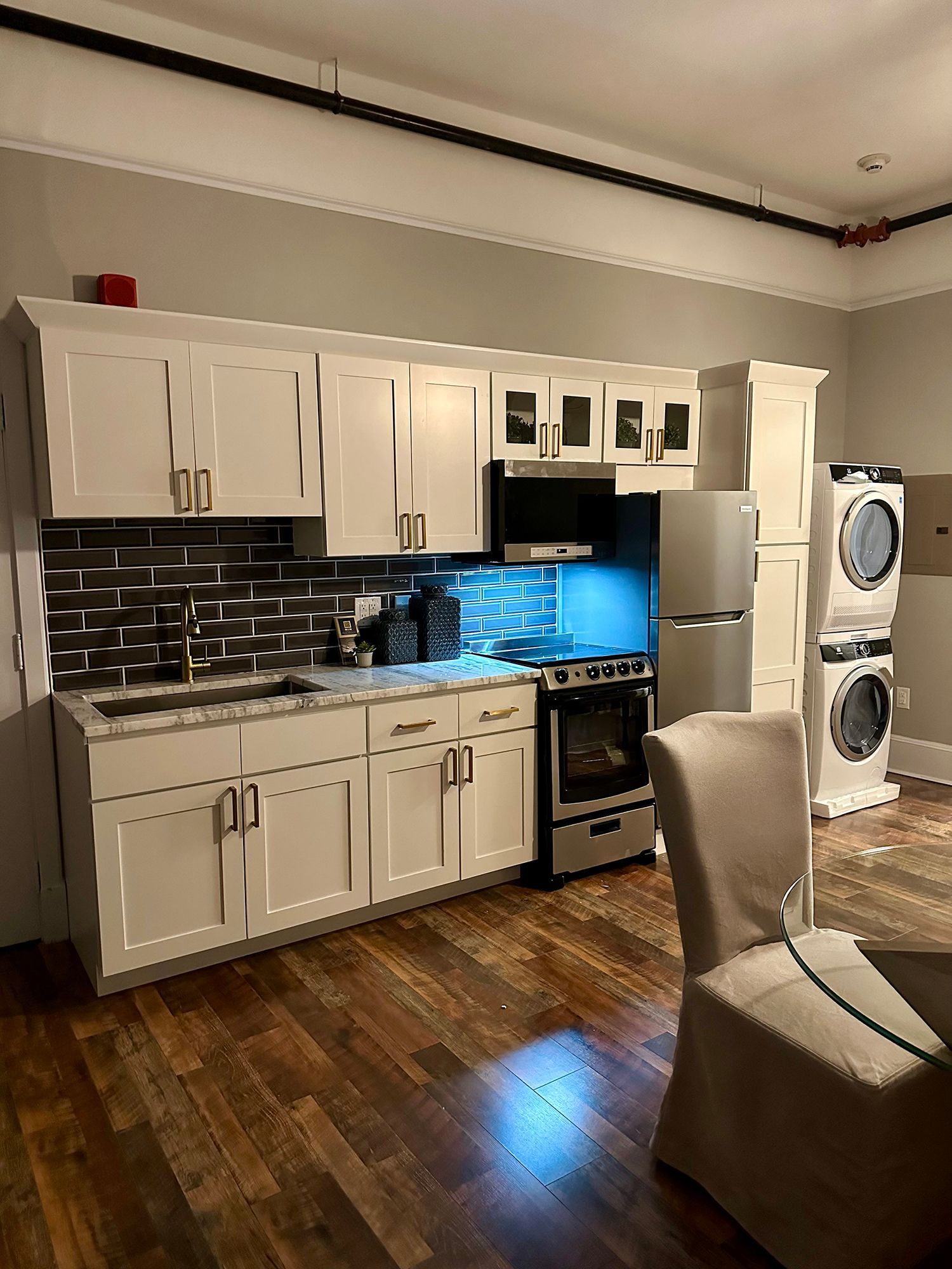A kitchen with white cabinets, a stove, a refrigerator, a washer and dryer, and a table.