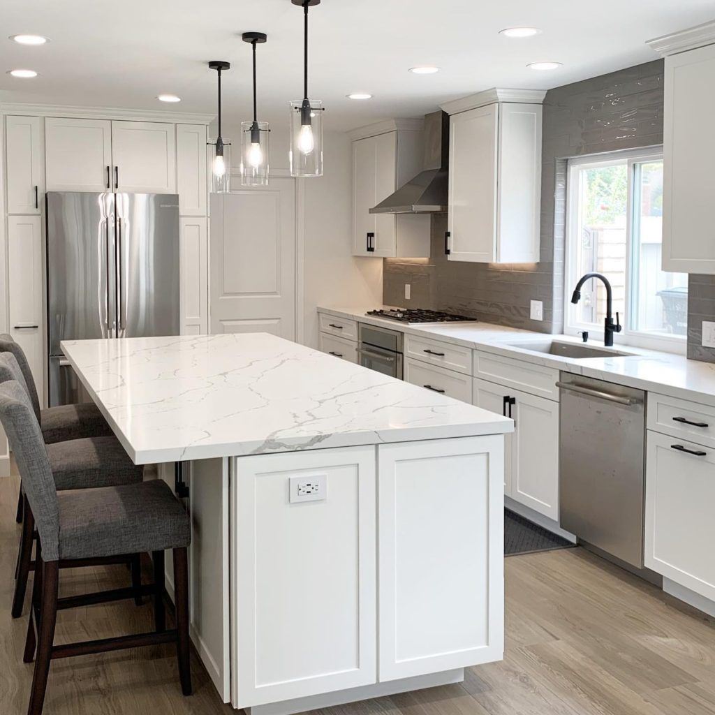 A kitchen with white cabinets and stainless steel appliances and a large island.
