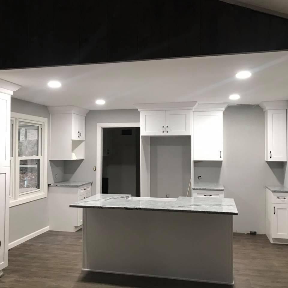 A kitchen with white cabinets and a large island in the middle.