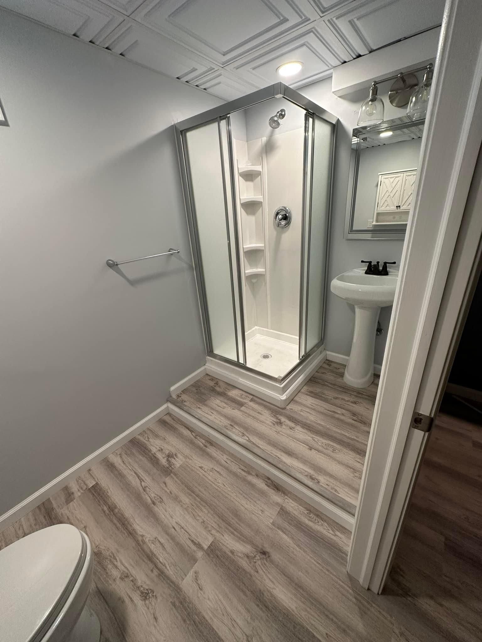 A bathroom with a shower , toilet , sink and mirror.