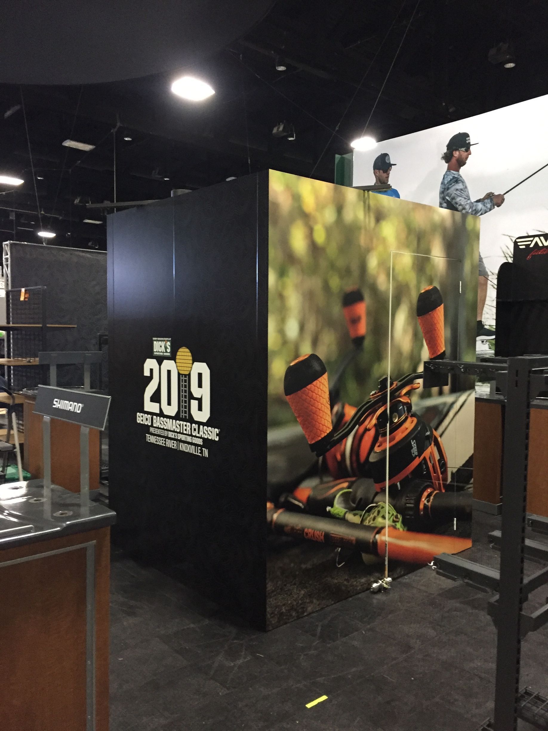 Black booth with 2019 logo and fishing scene. Men fishing on large outdoor backdrop.