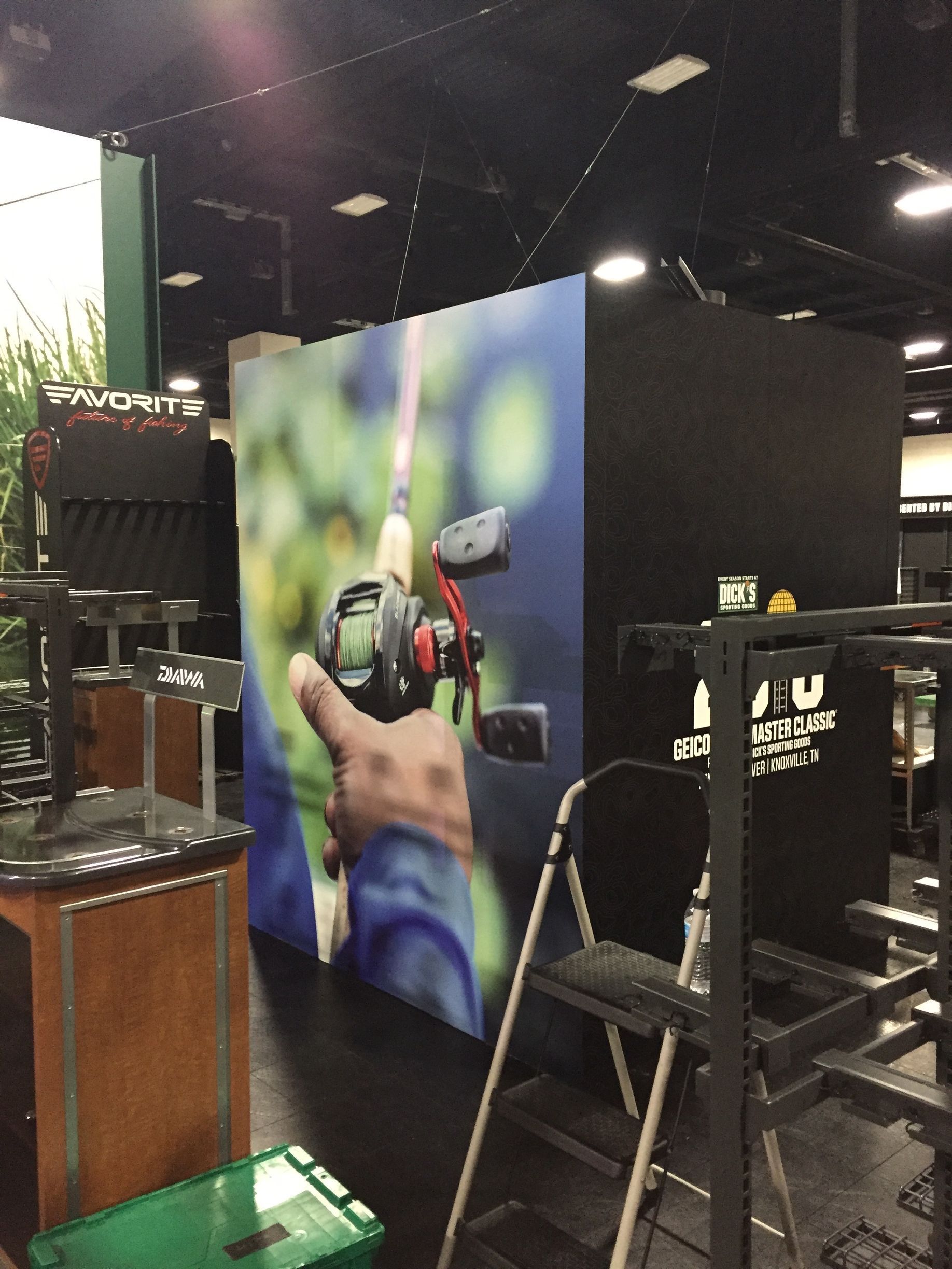 Fishing equipment display at a store; colorful wall advertisement featuring a fishing rod. Black and wooden store fixtures.