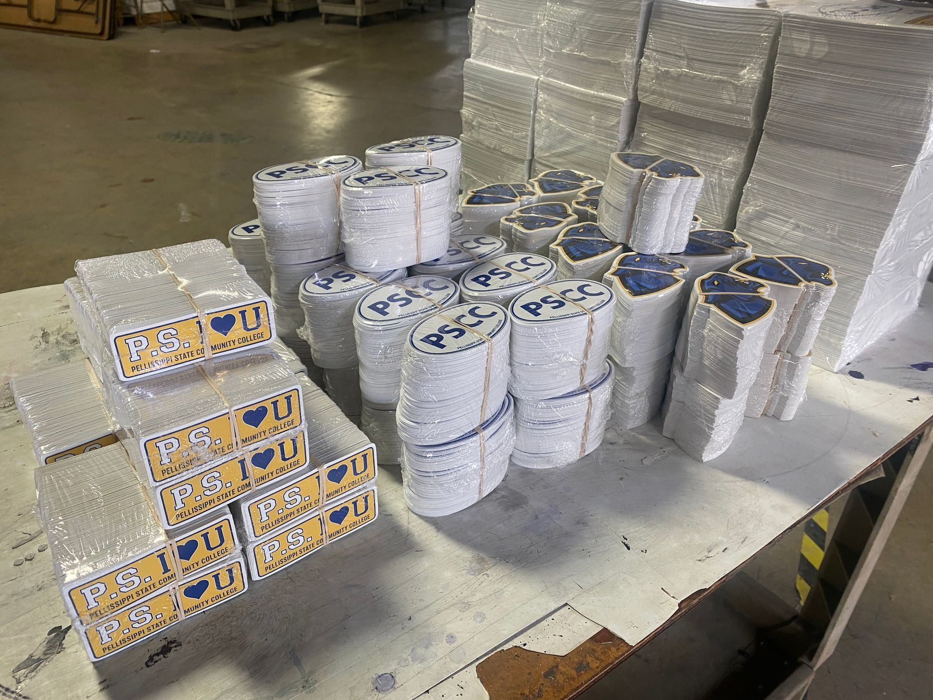 Stacks of wrapped blue and yellow items on a table in a warehouse setting.