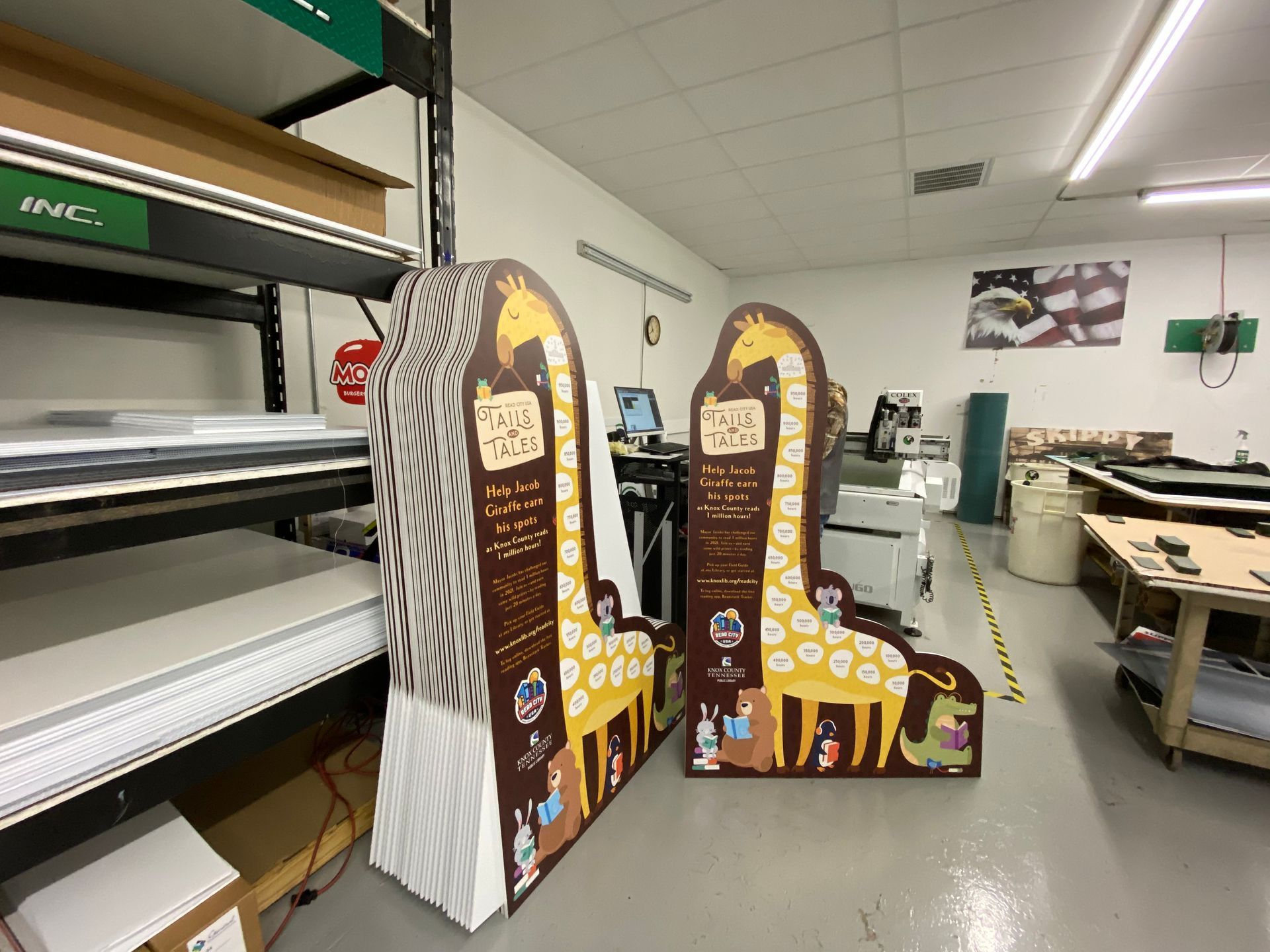 Cardboard giraffe and zebra cutouts in a warehouse. They feature educational text and colorful illustrations.