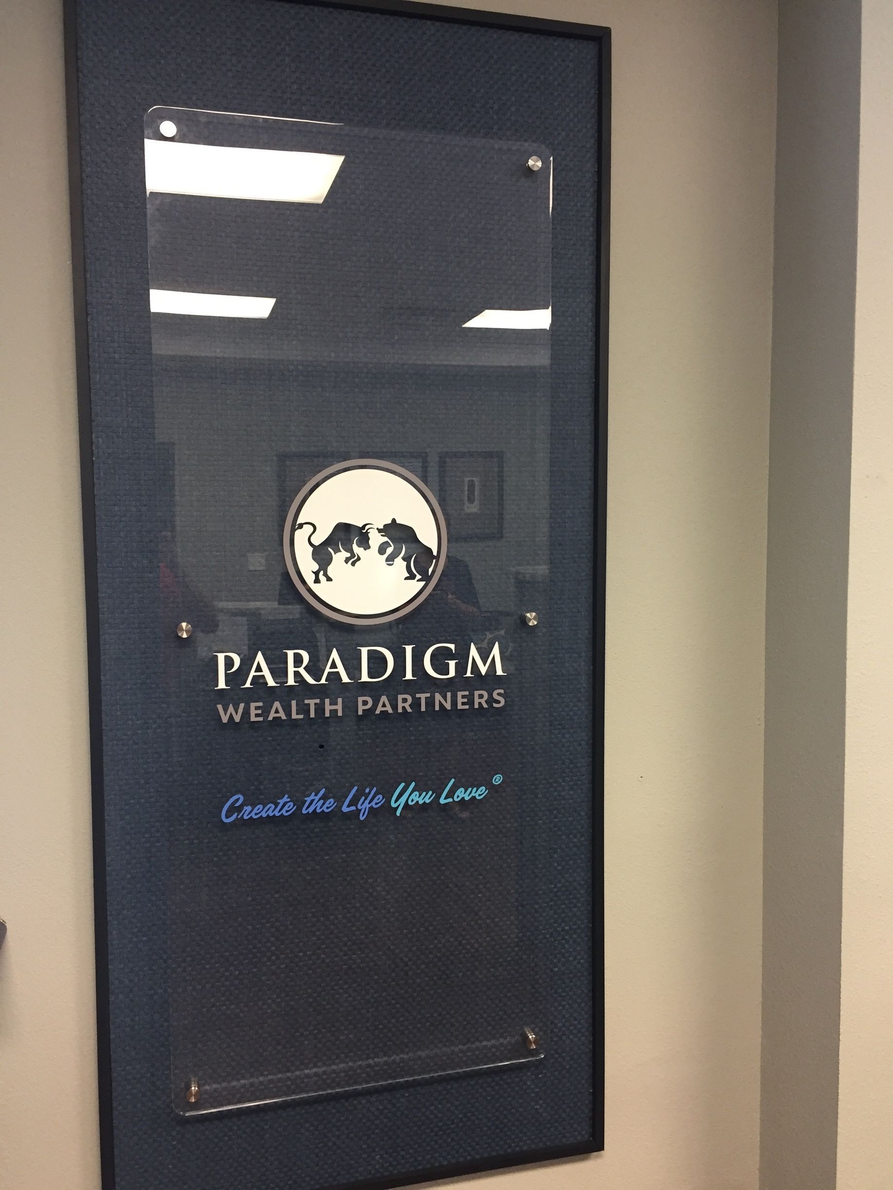 Sign for Paradigm Wealth Partners. A dark blue background with clear lettering and a logo featuring a bull and bear.