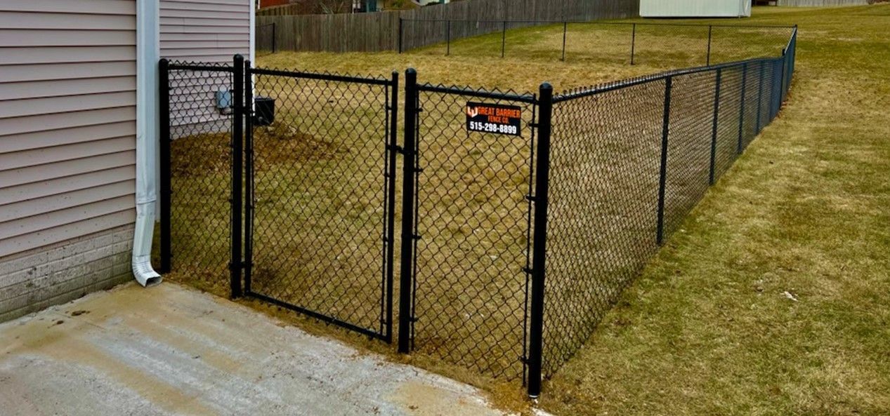 A chain link fence with a gate in the backyard of a house