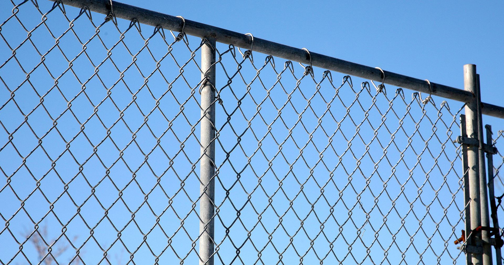 A chain link fence with a blue sky in the background