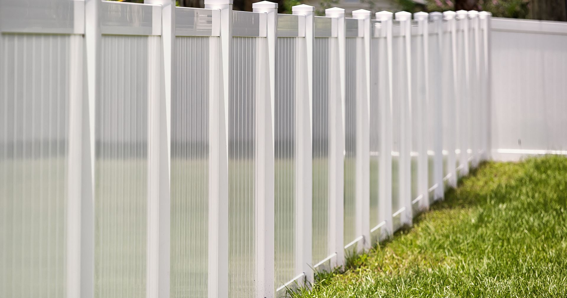 A white fence surrounds a swimming pool in a backyard.