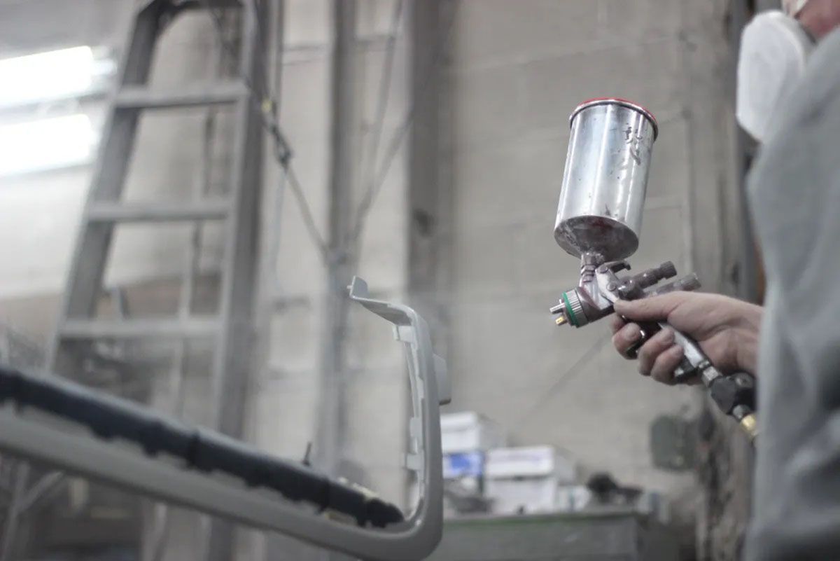 A man spray painting a car's part