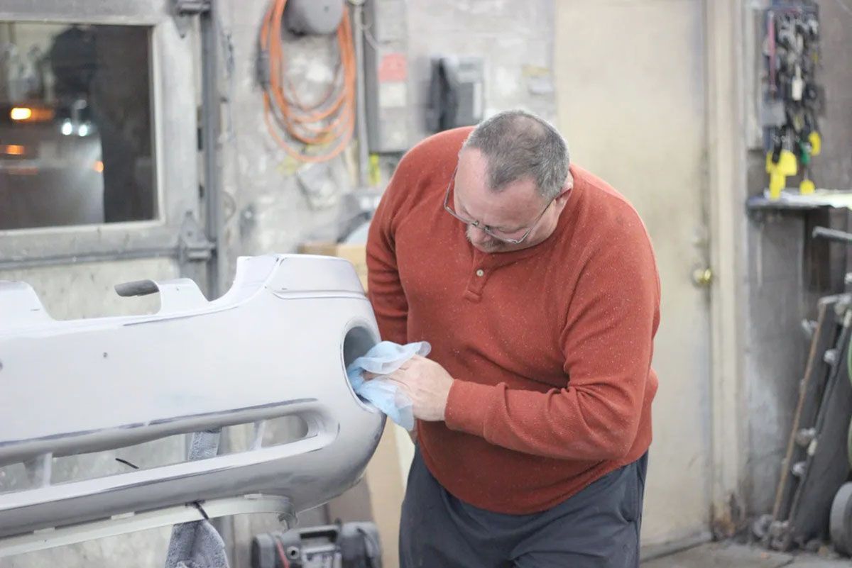 A man is working on a bumper in a garage