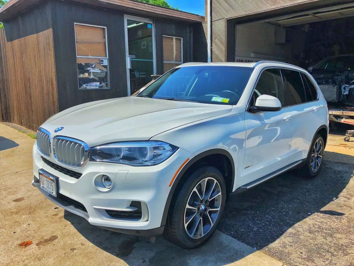 A white bmw is parked in front of a garage
