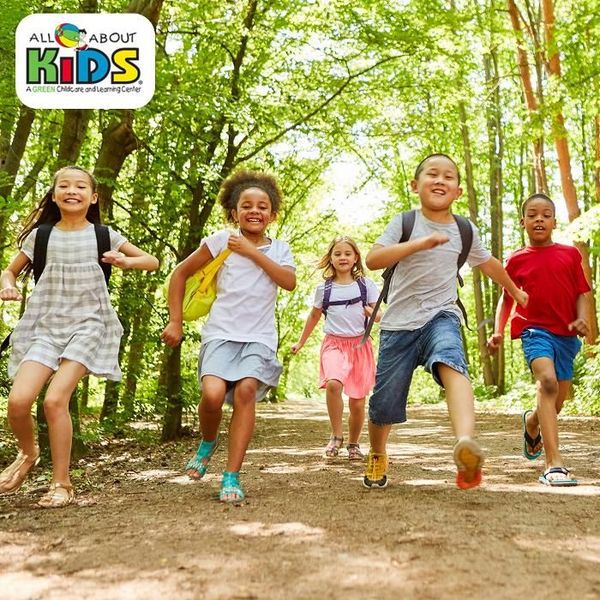 A group of kids are running down a dirt path in the woods