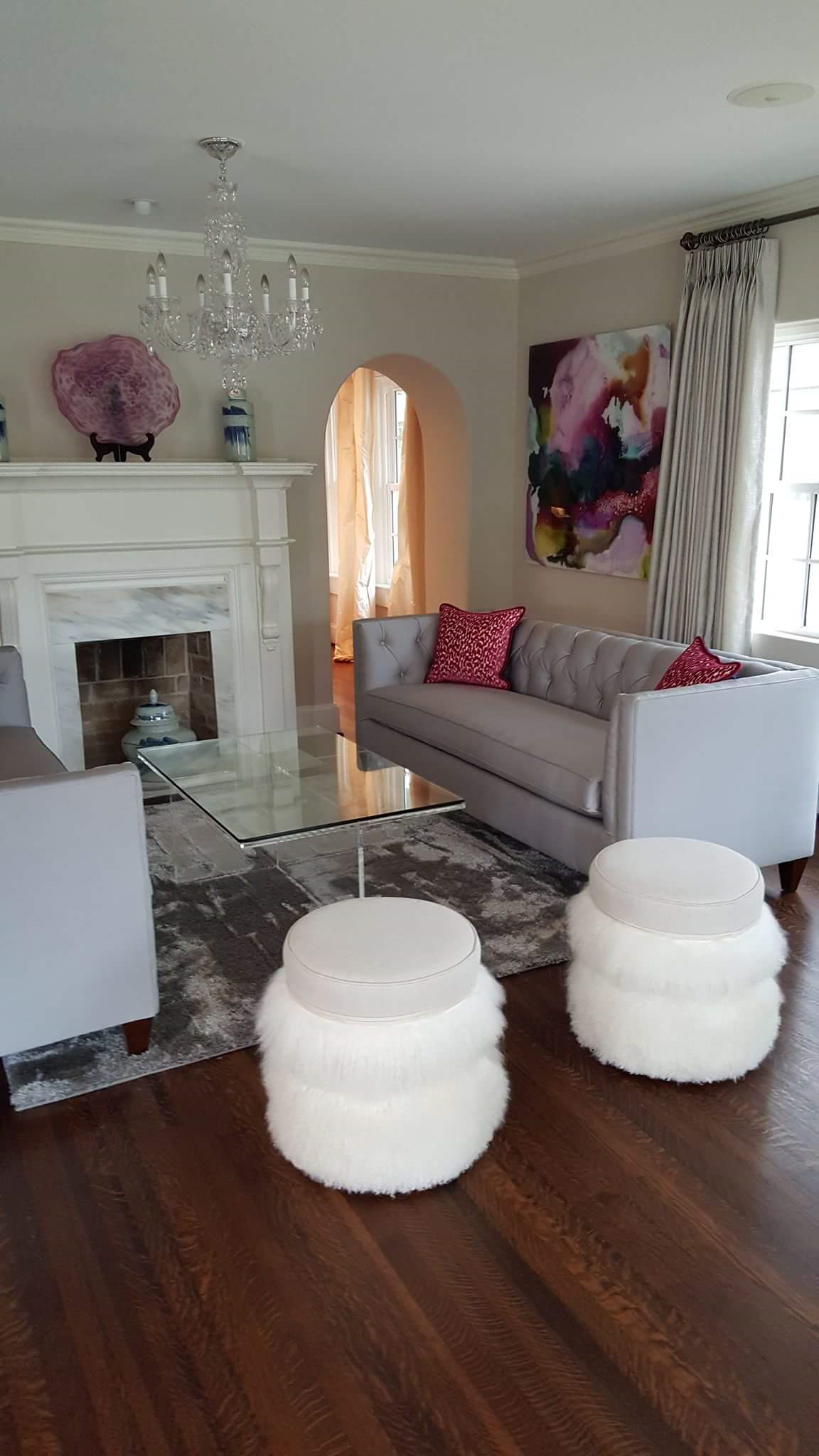 A living room with a couch, chairs, ottomans and a fireplace.