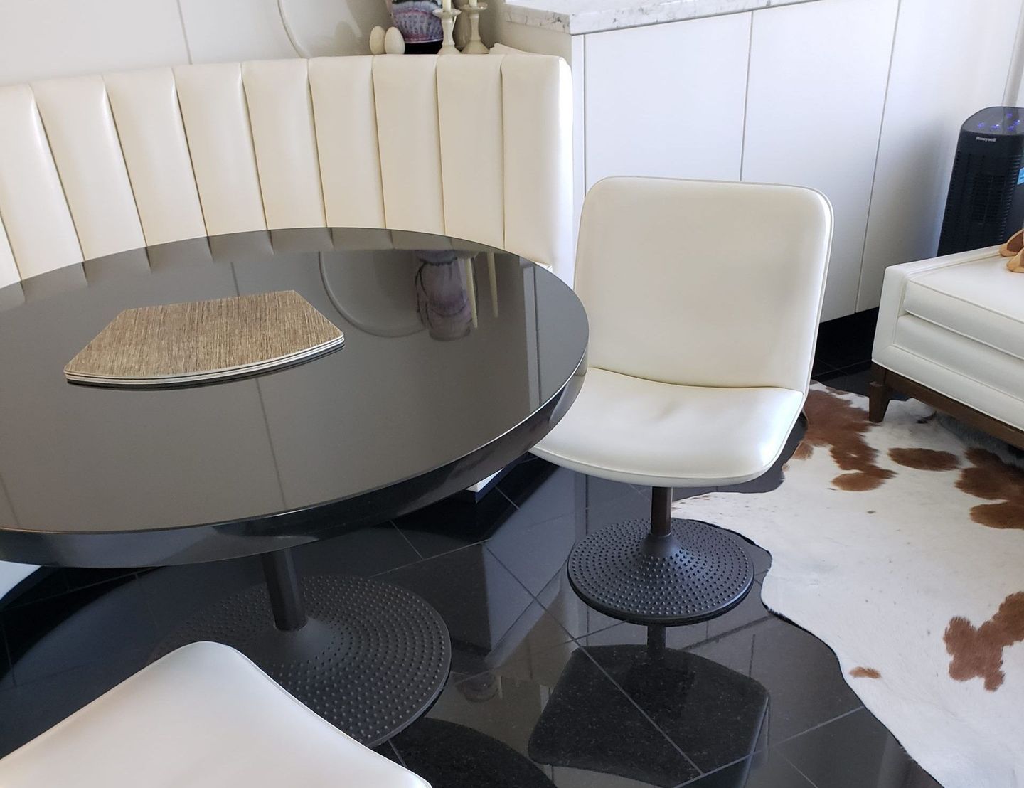 A dining room with a round table and white chairs.
