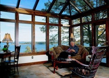A man sits on a couch in a living room with a view of a lake