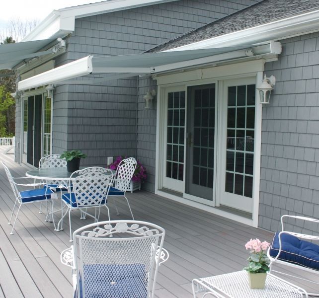 A deck with a table and chairs under an awning