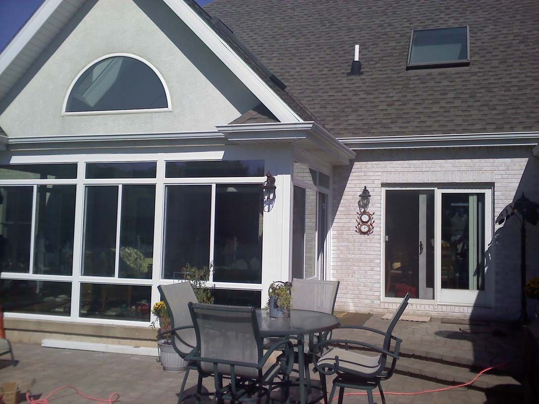 A white house with a lot of windows and a table and chairs in front of it