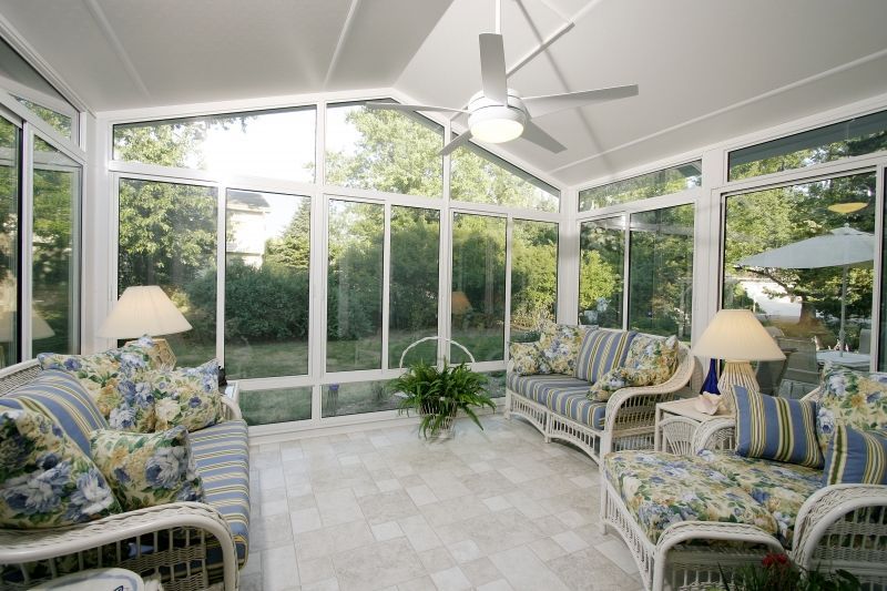 A sunroom with a lot of windows and a ceiling fan