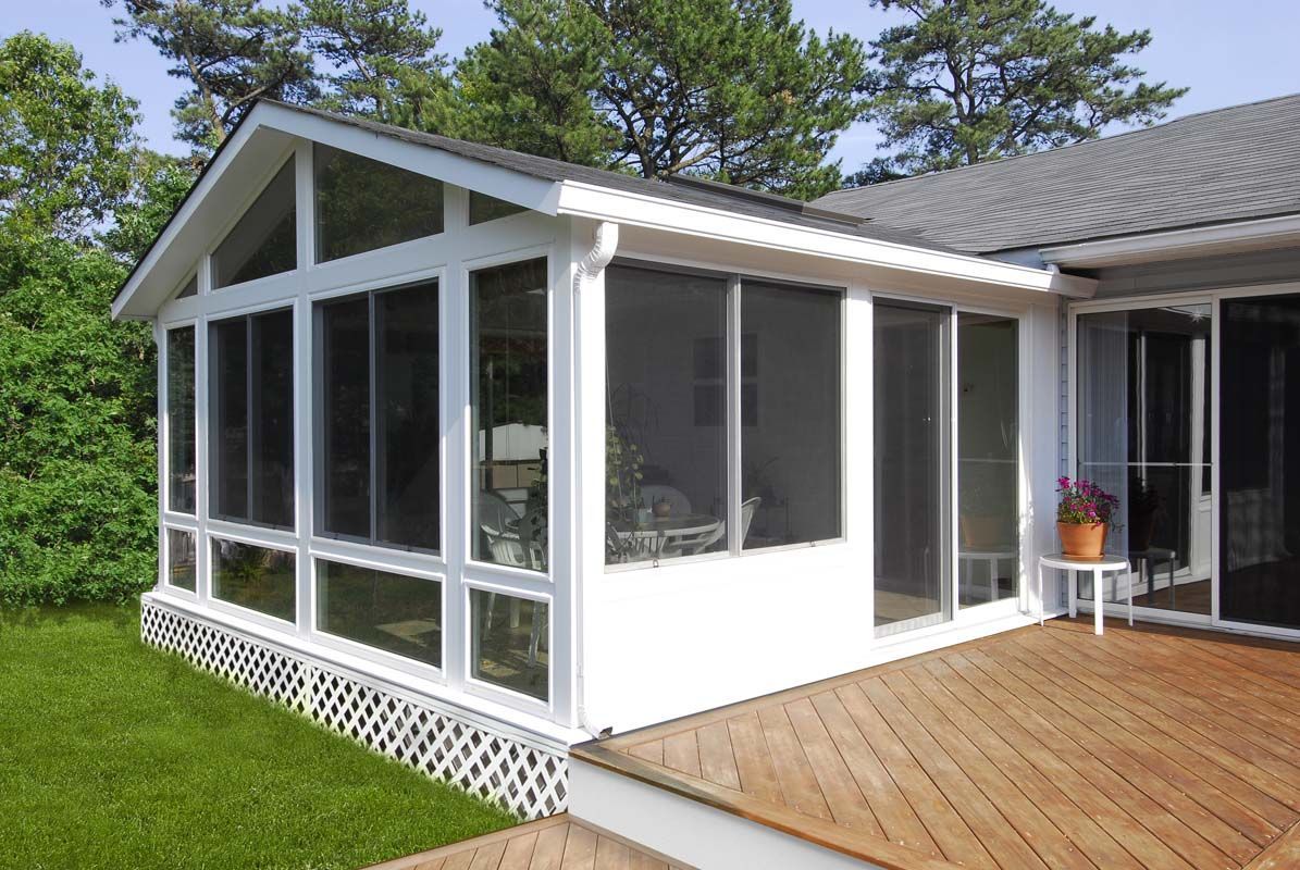 A house with a screened in porch and a wooden deck.