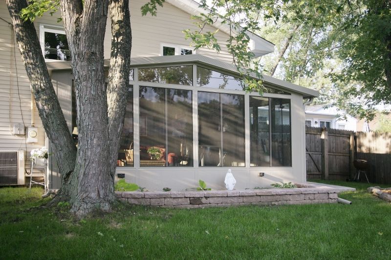A house with a screened in porch and a tree in front of it.